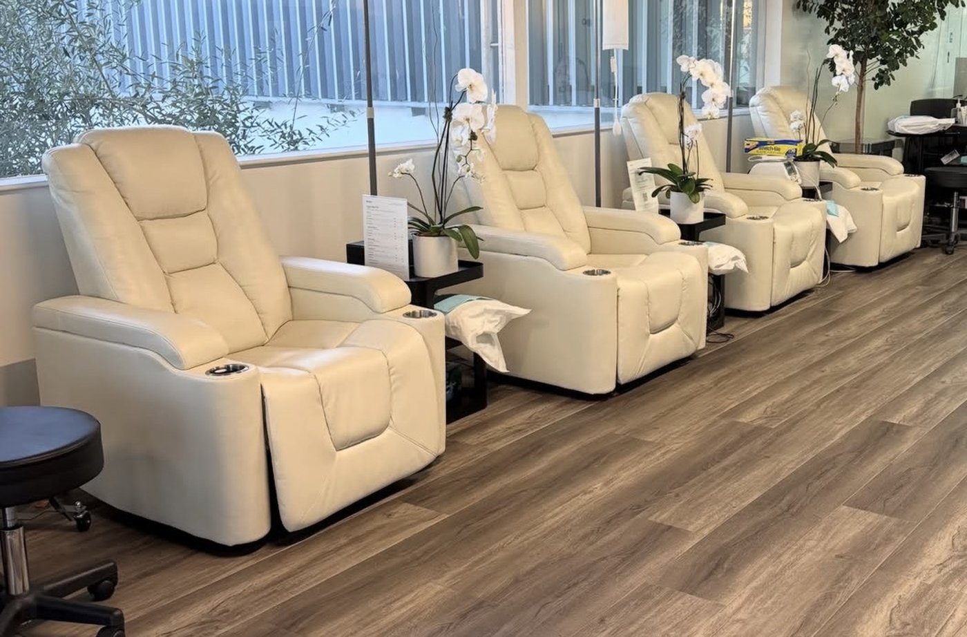 Four cream recliners with IV poles and orchids in the Range IV room, Newport Beach