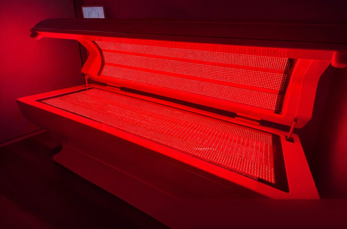 The full-body red light bed at Range Newport Beach, lid open and glowing red